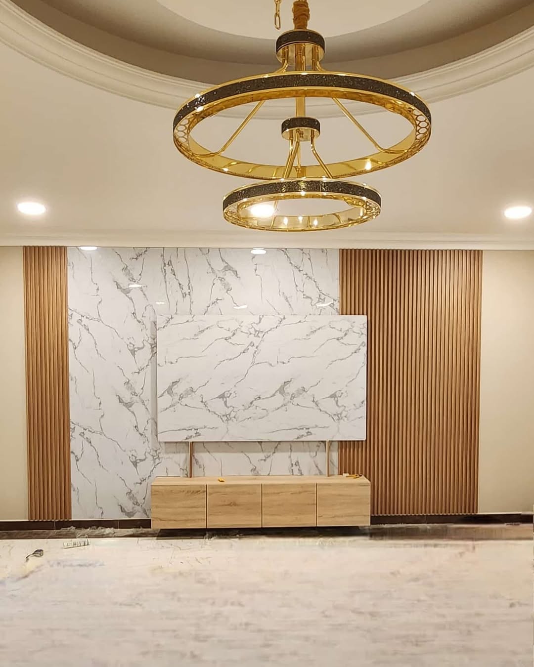 Marble feature wall with brass ring chandelier and wood-panelled TV unit