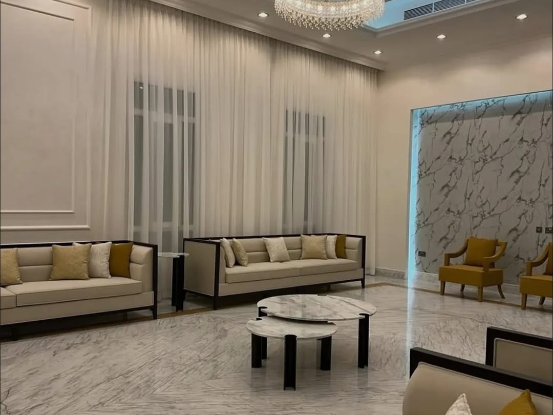 Living room with marble feature wall, crystal chandelier and mustard accent chairs